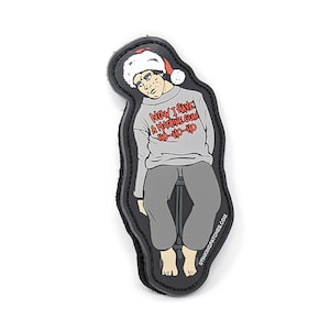 May include: A grey and black embroidered patch featuring a cartoon character wearing a Santa hat and a sweater that says "Now I have a machine gun ho-ho-ho".