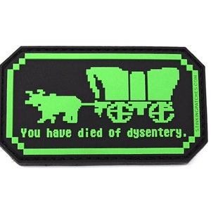 May include: Green and black embroidered patch with a pixelated image of a covered wagon pulled by an ox. The text "You have died of dysentery." is below the image.