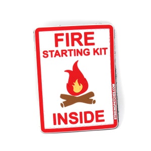 May include: A white patch with a red border and the text "FIRE STARTING KIT" in red. A red and yellow flame with brown logs is in the center of the patch. The text "INSIDE" is in red at the bottom of the patch. The text "STINKINGPATCHES.COM" is in black on the right side of the patch.