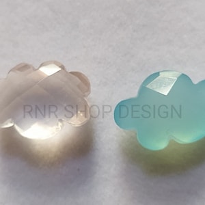 Puede incluir: Dos cuentas de piedra preciosa en forma de nube, una es rosa claro y la otra es azul claro. El texto "RNR SHOP DESIGN" es visible en la imagen.