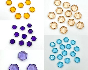 May include: Assortment of hexagonal glass gems in four colors: yellow, light brown, purple, and blue. The gems are arranged in groups of various sizes.