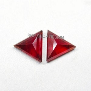 May include: Two red triangular gemstones with a faceted cut. The gemstones are set against a white background.