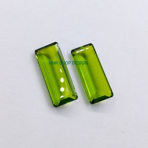 Può includere: Due pietre preziose rettangolari verdi con taglio a faccette. Le pietre preziose sono su uno sfondo bianco. RNR SHOP DESIGN è scritto al centro dell'immagine.
