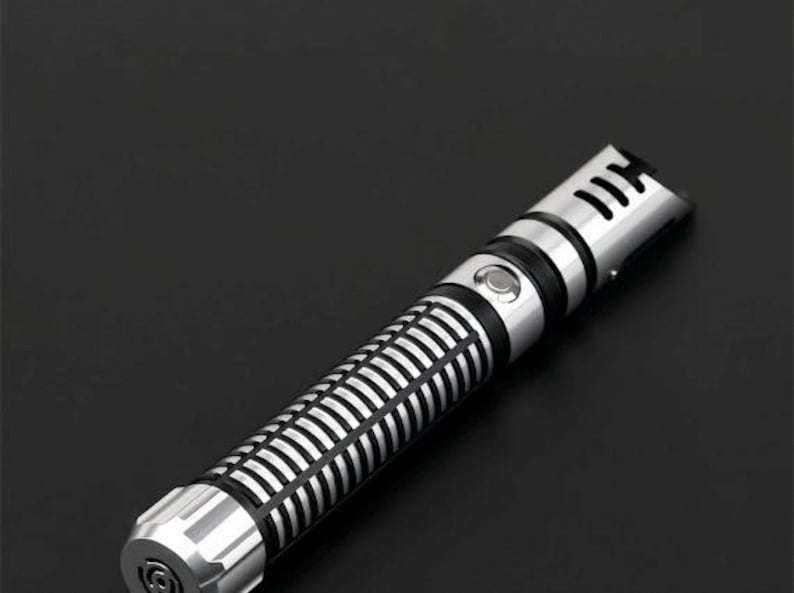 Pu&ograve; includere: Un'elica di spada laser argento e nera con un design dettagliato. L'impugnatura presenta un motivo a coste e un pulsante, mentre la parte superiore ha un design a forma di fessura. La spada laser &egrave; su uno sfondo nero.