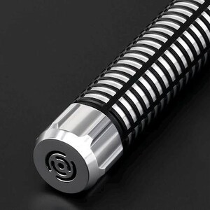 Pu&ograve; includere: Primo piano di un oggetto cilindrico con base in metallo argentato e corpo a motivi neri e argentati. L'estremit&agrave; dell'oggetto presenta un disegno circolare. L'oggetto &egrave; su una superficie nera.