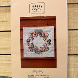 May include: A paper foundation pattern titled "Floral Wreath" by MH Designs. The pattern features a colorful floral wreath design, measuring 14.5 inches by 14.5 inches. The cover has the MH Designs logo in a black rectangle.
