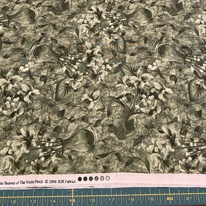 May include: A green fabric with a repeating pattern of white flowers in a vase. The fabric has a vintage look and feel. The text "Violetta by Debbie Beaves of The Violet Patch 2005 RJR Fabrics" is printed at the bottom of the fabric.
