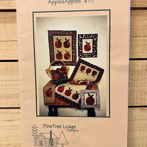 May include: A quilt pattern booklet featuring a red apple design. The booklet is titled "ApplesApples #117" and is by "PineTree Lodge Designs".