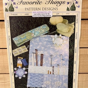 May include: A sewing pattern for a knitting needle holder, pin cushion, and straight needle case. The pattern is called "Pins & Needles" and is from the "Favorite Things" pattern designs. The pattern is on a light brown background with a blue and white floral pattern.