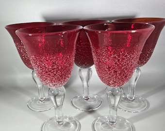 May include: Set of six red wine glasses with a textured, bubbly surface. The glasses have clear stems and bases.
