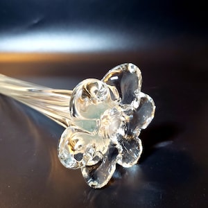 May include: A clear glass flower vase with a fluted stem and a flower-shaped opening.