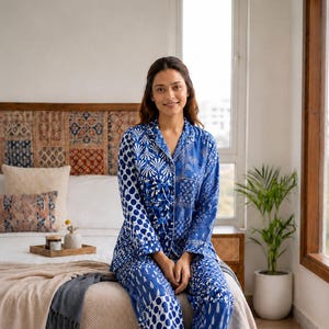 May include: A two-piece pajama set featuring a long-sleeved button-down shirt and matching trousers, both crafted from fabric with a patchwork design of blue and white patterns, including polka dots, floral motifs, and geometric shapes.