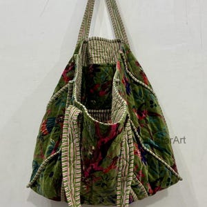 May include: Green floral tote bag with striped handles. The bag features a quilted design with a vibrant floral pattern in shades of red, pink, and green. The handles are a combination of green and white stripes.