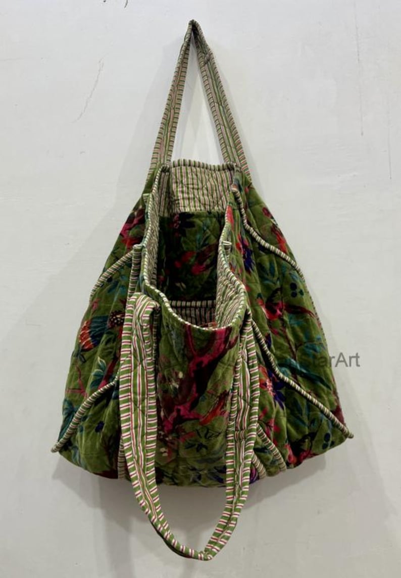 May include: Green floral tote bag with striped handles. The bag features a quilted design with a vibrant floral pattern in shades of red, pink, and green. The handles are a combination of green and white stripes.