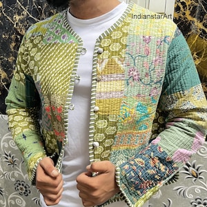 May include: A green, blue, and pink patchwork quilted jacket with a button closure. The jacket has a white stripe down the front and a white collar.