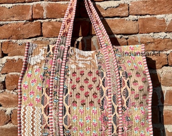 Può includere: Una grande borsa tote patchwork realizzata in tessuto trapuntato in tonalità rosa, marrone e bianco. La borsa presenta una varietà di motivi floreali e geometrici. La borsa ha due lunghi manici.