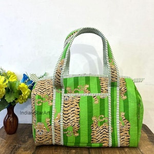 May include: A green and tan tiger print tote bag with a striped pattern. The bag has two handles and a small pocket on the front. The bag is sitting on a wooden surface.