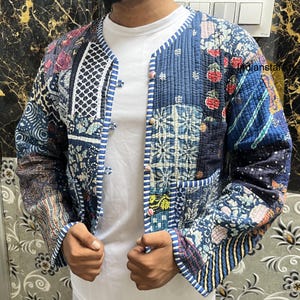May include: A blue and white patchwork quilted jacket with a button closure. The jacket has a floral and geometric pattern.