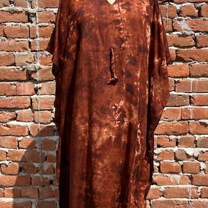 May include: A long, brown, tie-dye kaftan with a V-neck and short sleeves. The kaftan is made of a soft, flowing fabric and has a relaxed fit.