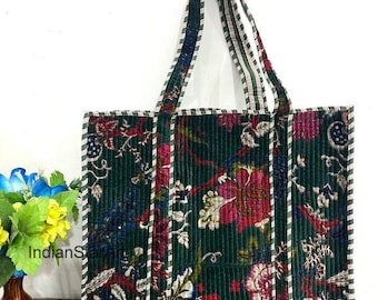 May include: A green floral tote bag with a corduroy texture. The bag features a pattern of red, pink, and blue flowers. White stripes edge the bag and handles, which are green with white and red stripes. The bag is on a wooden surface.