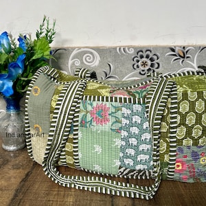 Könnte beinhalten: Eine grüne und weiße Patchwork-Reisetasche mit Blumen- und Elefantenmuster. Die Tasche hat zwei lange Trageriemen und ist aus gestepptem Stoff.