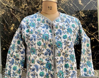 Puede incluir: Una chaqueta acolchada blanca con estampado floral azul y verde. La chaqueta tiene cierre de botón y un ribete a rayas.