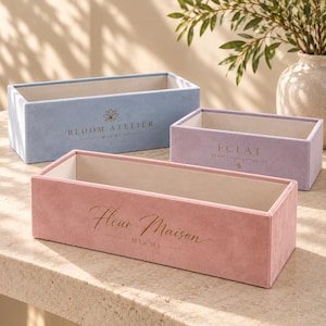 May include: Three rectangular velvet storage boxes in light blue, lavender, and dusty pink. Each box features a cream-colored interior and gold-toned text on the front: Bloom Atelier Miami, Éclat Beauté-Intemporelle, and Fleur Maison Miami.