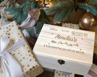 May include: A wooden Christmas Eve box with a personalized inscription that reads "Amelia's Christmas Eve Box". The box is decorated with a reindeer and sleigh design and has a brass latch.
