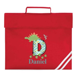 May include: Red book bag with white stripes. The bag features a dinosaur design with the letter D and the name Daniel.