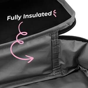 Puede incluir: Primer plano del interior de una bolsa aislante gris. El texto "Fully Insulated" se muestra en blanco, con una flecha rosa que apunta hacia el interior. La bolsa tiene una cremallera negra y un ribete gris.