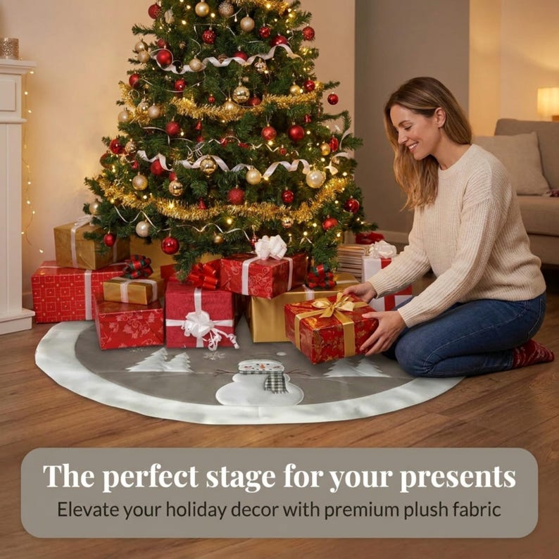 May include: A round grey Christmas tree skirt featuring a white snowman graphic with a black and white plaid scarf, surrounded by white tree silhouettes and snowflakes, finished with a wide white plush border trim around the circular edge.
