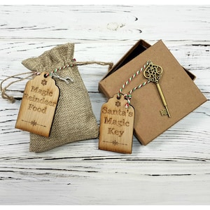 Puede incluir: Dos etiquetas de madera con cuerda, una dice "Magic Reindeer Food" y la otra dice "Santa's Magic Key". Tambi&eacute;n hay una peque&ntilde;a bolsa de arpillera y una caja con una llave dorada en la imagen.