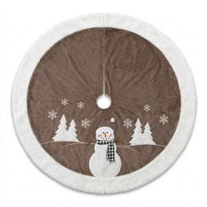 May include: A round Christmas tree skirt featuring a brown velvet centre with a white plush border. The design includes a white snowman wearing a black and white buffalo check scarf, surrounded by white embroidered pine trees and snowflakes.
