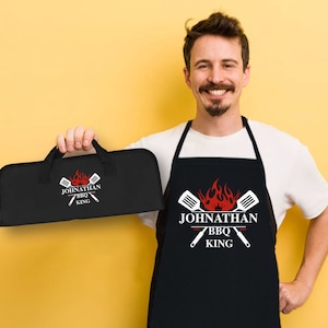 May include: Black BBQ apron with the text "Johnathan BBQ King" and a red flame design. A matching black tool roll with the same design and text is also shown.