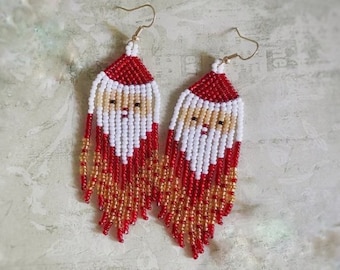 May include: A pair of beaded earrings featuring a Santa Claus design. The earrings are red, white, and gold with a fringe of beads.