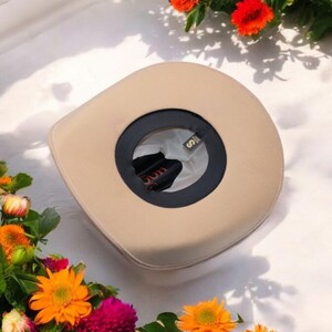 Peut inclure: Un chapeau de cowboy beige avec un bandeau noir et une petite &eacute;tiquette dor&eacute;e sur laquelle est inscrit "S". Le chapeau est entour&eacute; de fleurs orange et roses.