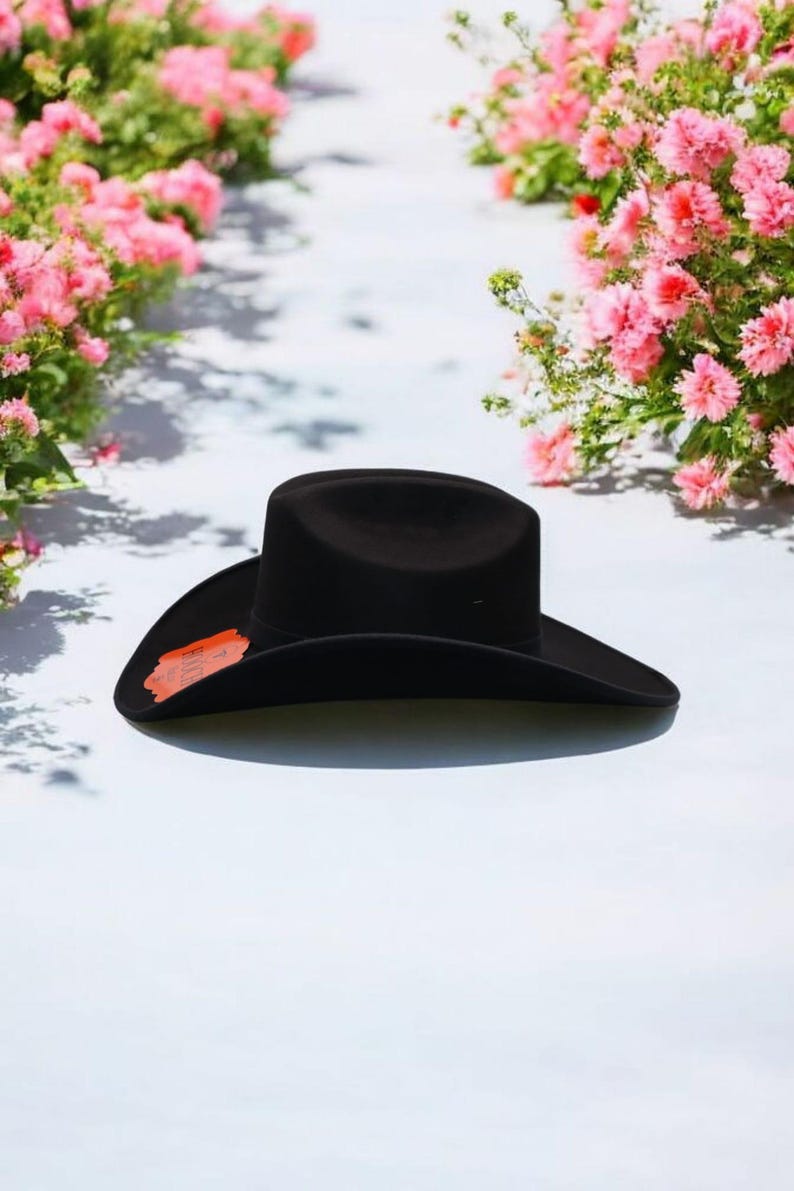 Puede incluir: Un sombrero vaquero de fieltro negro con un ala ancha. El sombrero est&aacute; sobre una superficie blanca.