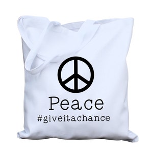 May include: White canvas tote bag with a black peace sign and the text "Peace #giveitachance"