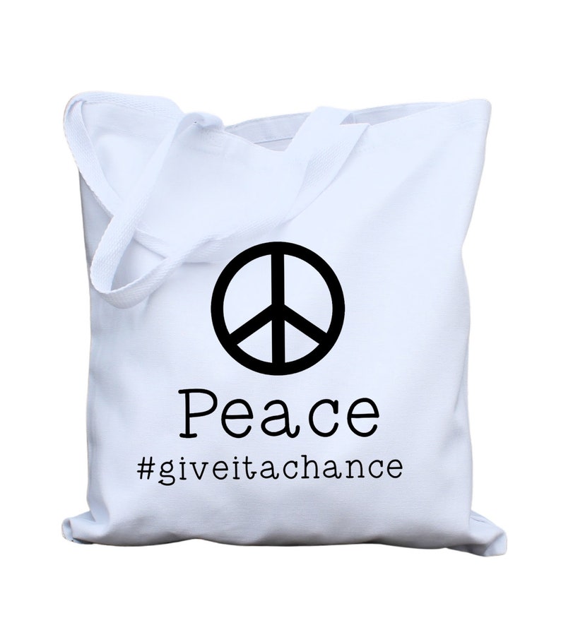 May include: White canvas tote bag with a black peace sign and the text "Peace #giveitachance"