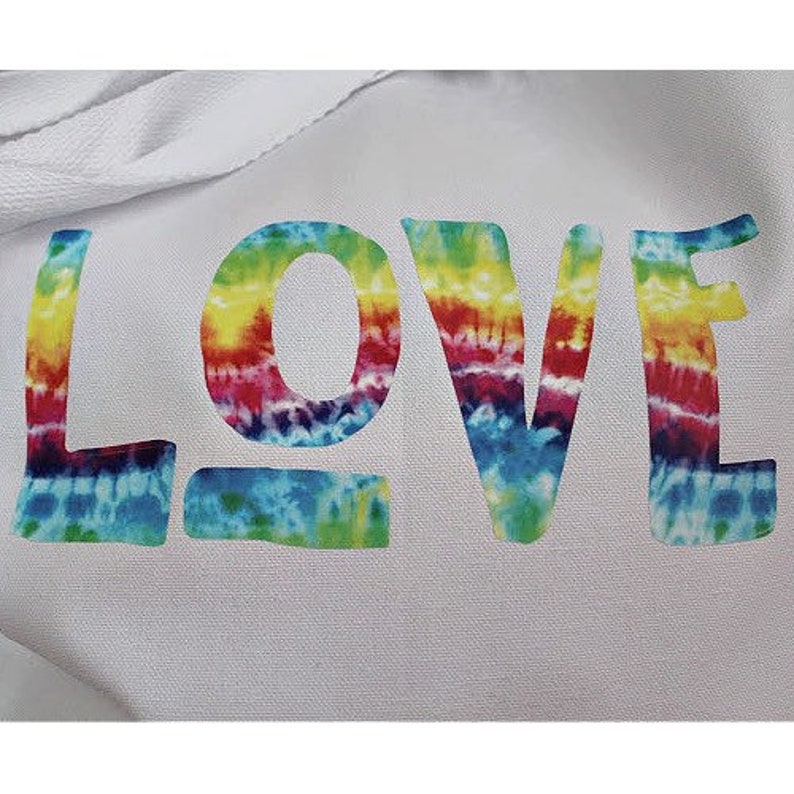 May include: White tote bag with the word "LOVE" written in rainbow tie-dye lettering.