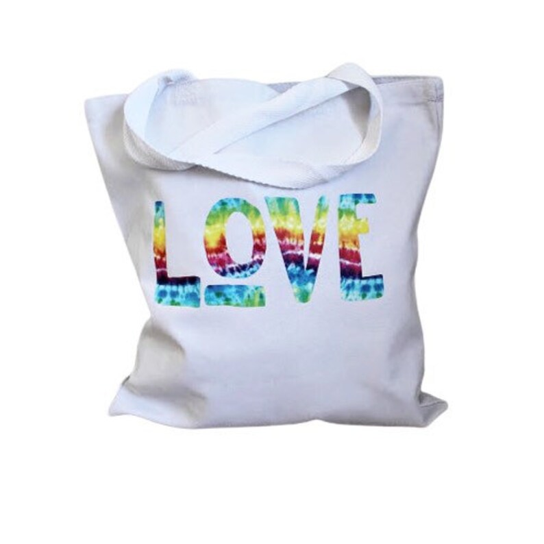May include: White canvas tote bag with the word "LOVE" printed in rainbow tie-dye colors.