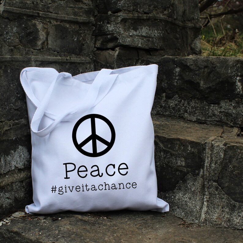 May include: White canvas tote bag with a black peace sign and the text "Peace #giveitachance".