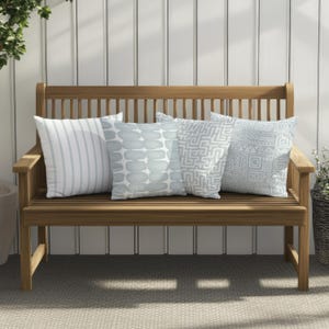 May include: A wooden bench with four light blue throw pillows. The pillows have different patterns, including stripes, geometric shapes, and abstract designs.