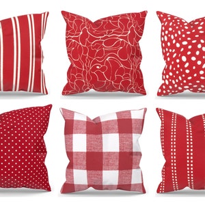 Pode incluir: Seis almofadas decorativas vermelhas e brancas. As almofadas têm padrões diferentes, incluindo listras, bolinhas e um design floral.