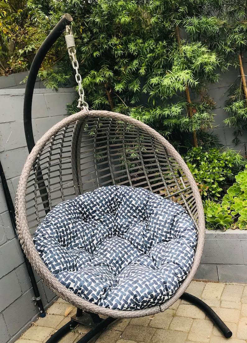 May include: A gray wicker hanging chair with a black metal frame and a blue and white patterned cushion.
