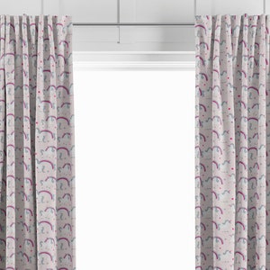 May include: A pair of pink curtains with a white unicorn and rainbow pattern. The curtains are hung on a white wall.