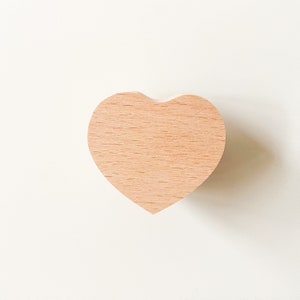Op de afbeelding: Een lichtbruin houten ornament in de vorm van een hart.