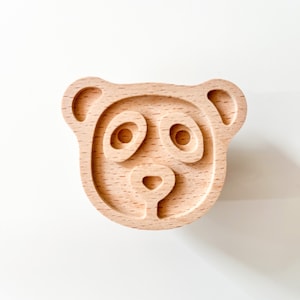 Op de afbeelding: Een houten stempel met een berenkop, een hartvormige neus en twee ronde ogen.