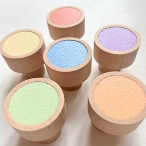 Könnte beinhalten: Sechs Holzgriffe mit bunten runden Oberseiten. Die Griffe sind in den Farben Gelb, Hellblau, Hellgrün, Orange, Rosa und Koralle.