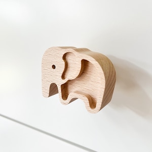 Op de afbeelding: Een houten trekknop in de vorm van een olifant met een uitgesneden ontwerp. De knop is gemaakt van licht hout en heeft een gladde afwerking.